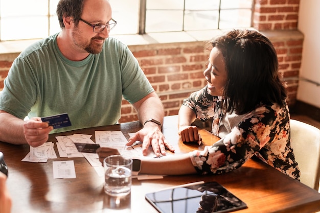 Two people sitting at a table, one handing their credit card to the other with a pen and an application form nearby, symbolizing the process of adding an authorized user to an account. The atmosphere is supportive and collaborative.