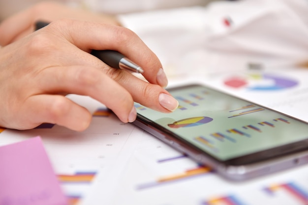 A close-up shot of a young adult's hands using a smartphone app to track expenses, with colorful graphs and charts illustrating their spending habits.