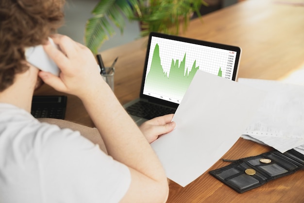A person using a laptop to analyze stock market data and charts, illustrating the importance of research and informed decision-making in investing. The scene takes place in a modern, well-lit home office.