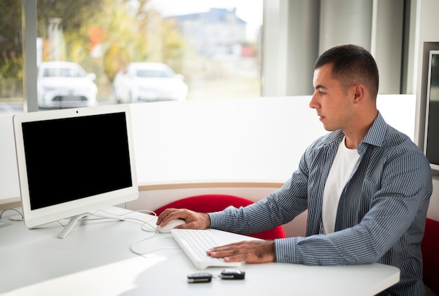 A person in their early 30s sitting at a desk, using a financial planning software on their laptop. The software displays charts and graphs related to retirement planning and investment growth. Books on personal finance are stacked neatly on the desk.