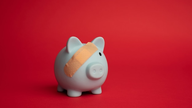 A piggy bank with a bandage on it, symbolizing the emergency fund protecting against unexpected financial setbacks, with financial charts in the background.