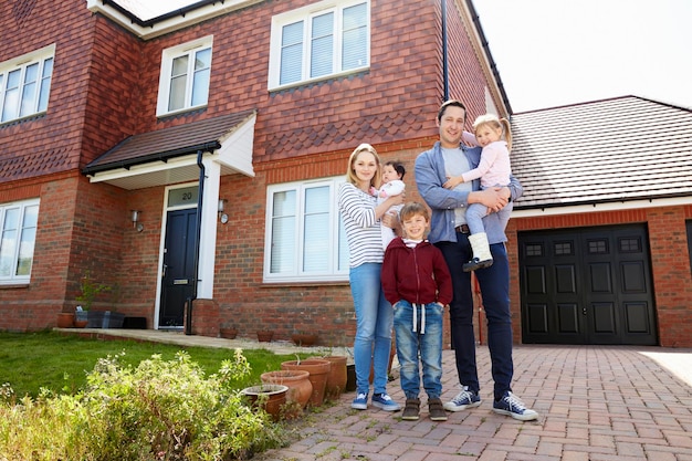 A family standing in front of their new house, smiling. The image conveys a sense of security and accomplishment, highlighting the importance of home insurance.