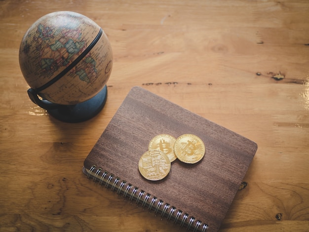 A stack of gold coins with a shield symbol on it, next to a calculator and a pen, placed on top of a newspaper with financial headlines. The background is blurred.