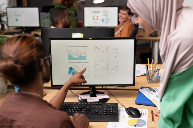 A diverse group of people looking at charts and graphs on a large screen, with each person having a different expression - some are smiling, some are concentrated. The setting is a modern, well-lit office space.