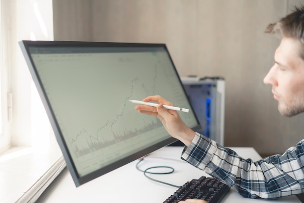 A person analyzing financial data on a screen with a graph showing losses being offset by gains, symbolizing the tax-loss harvesting strategy in investment.