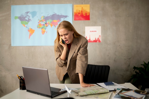 A person sitting at a desk, looking stressed while surrounded by tax documents and a world map.