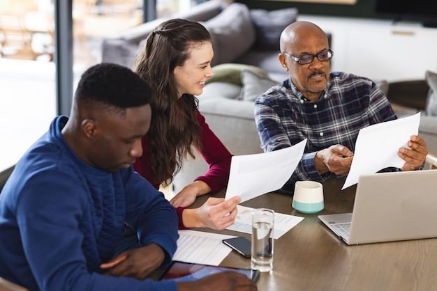 A diverse group of people sitting at a table, discussing investment strategies and using tablets and laptops to analyze data.
